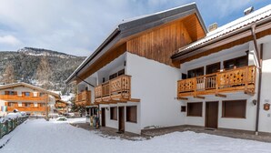 A snow-covered courtyard with wooden balconies and a mountain backdrop.