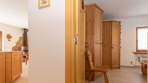 A room with wooden cabinets, a chair, and a wooden wardrobe. - Appartamento Miralago (Alleghe)
