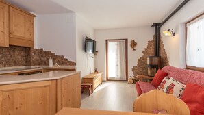 A cozy living area with wooden furniture, a fireplace, and a television. - Appartamento Miralago (Alleghe)