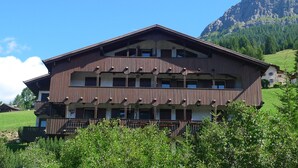 Un immeuble à plusieurs étages, doté de balcons, qui se dresse sur fond de montagnes.