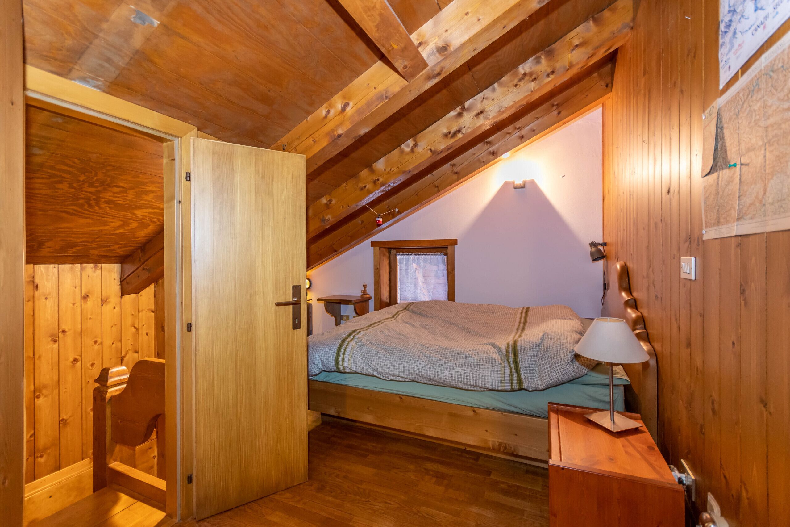 Ein Zimmer mit Holzboden, einem Schlafplatz in der Heidelandschaft, einem kleinen Tisch und einem Stuhl.