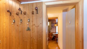 A wooden hallway with a radiator on the right and a door with hooks on the left.