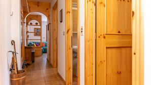 A wooden hallway with a rustic interior, leading to a living area with a sofa and a fireplace. - Casa Maura (Soraga)