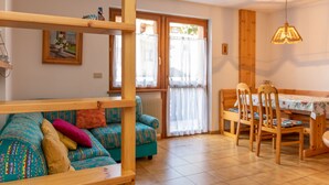 A cozy living room with a sofa, chairs, a dining table, and a wooden partition. - Casa Maura (Soraga)