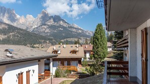 A mountain-view hotel with a patio, wooden benches, and a view of the mountains.