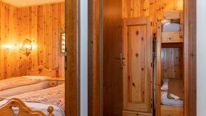 A wooden-paneled room with two single beds, a wardrobe, and a nightstand with a lamp.