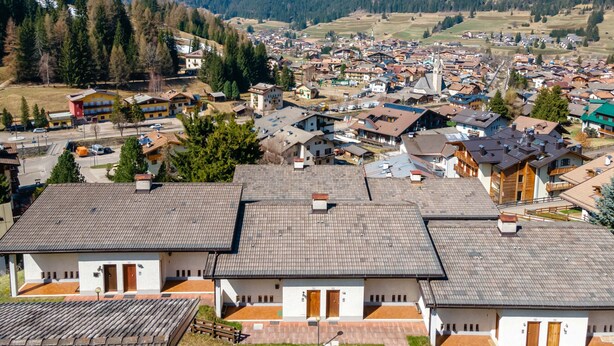 A town with a mix of residential and commercial buildings, surrounded by mountains and forests.