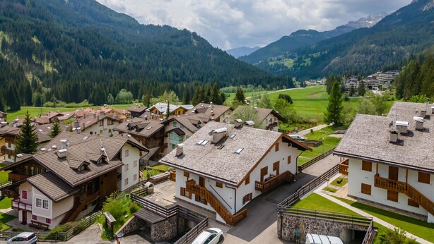 A mountain village with traditional wooden houses, a paved road, and a valley with dense forests. - Casa Coli (Mazzin)