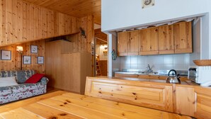 A wooden interior with a sofa, a bench, and a kitchen area with wooden cabinets and a sink. - Petit Arnica (Selva di Cadore)