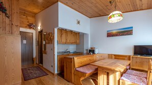 A wooden interior with a kitchen, dining area, and a TV. - Petit Arnica (Selva di Cadore)