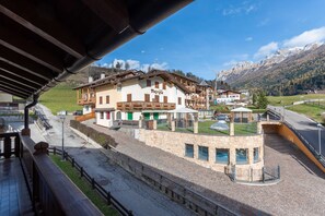 A hotel with a stone facade, multiple balconies, and a view of a mountainous landscape. - Casa Blue Sky (Moena)