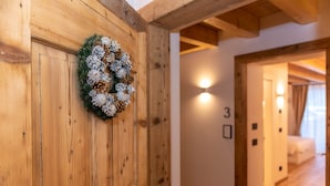 Een houten muur met een krans, een bord met het cijfer '3' en een gang die leidt naar een kamer met een bed.