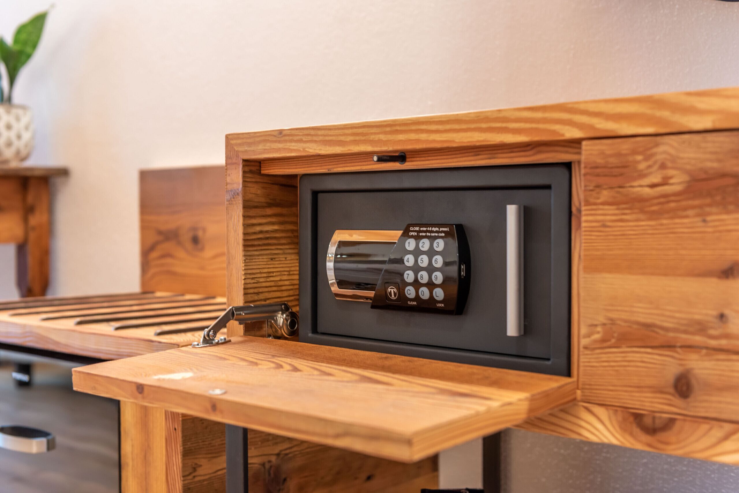 A secure, built-in safe with a keypad lock, integrated into a wooden structure, likely in a hotel room.