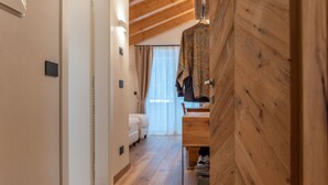 A narrow hallway with wooden flooring leading to a room with a bed and a window. - B&B El Lares 2 (Canale d´Agordo)