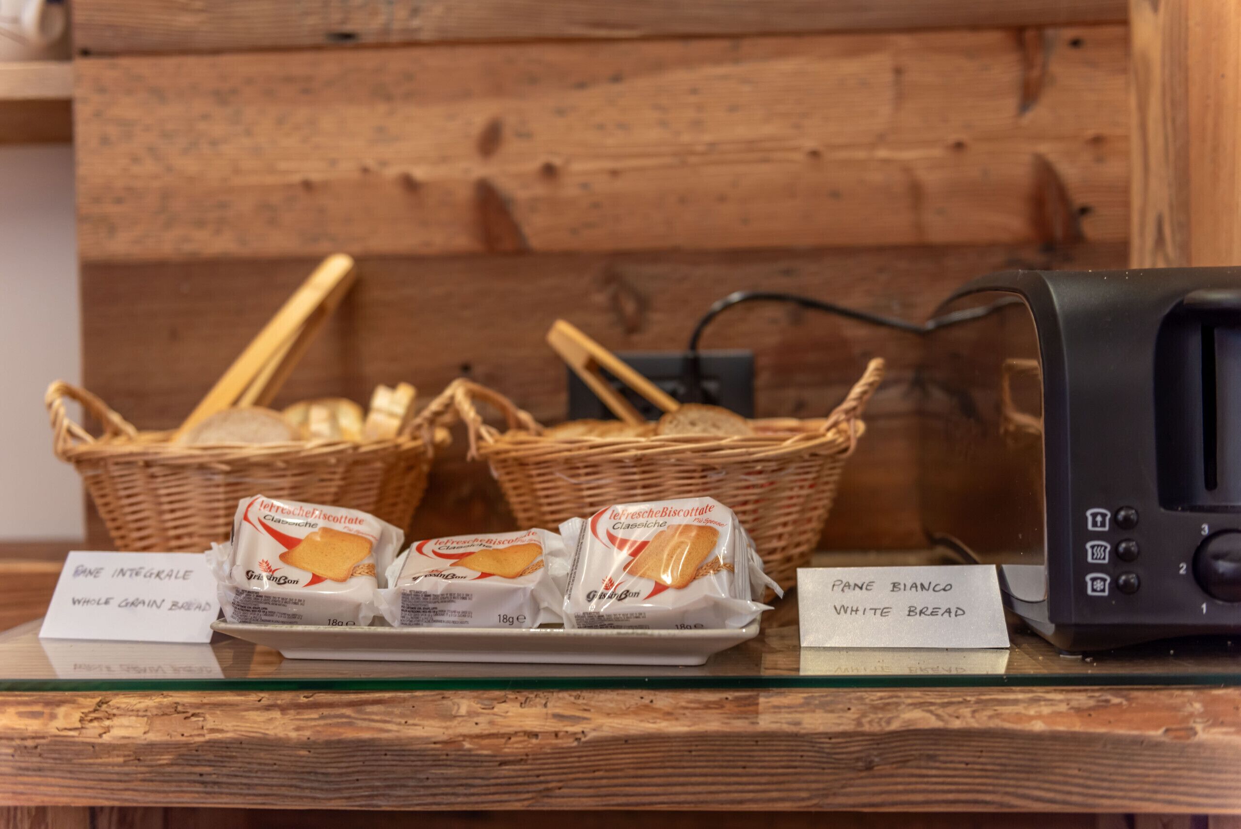 A display of bread and biscuits with labels indicating 'Pane Integrale Whole Grain Bread' and 'Pane Bianco White Bread.'