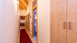 Een hal met houten vloer, een rood tapijt en houten deuren naar een badkamer en een eetruimte.
