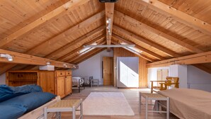 A cozy attic bedroom with wooden beams, a bunk bed, a desk, and a chair. - Casa Narciso (Rocca Pietore)