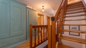 A staircase with wooden railings and a handrail, leading to a landing with a light fixture. - Casa Narciso (Rocca Pietore)