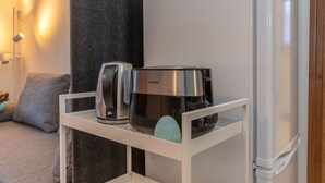 Un coin cuisine doté d’un plan de travail blanc sur lequel sont posés une machine à café Philips et un grille-pain.