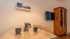 Un espace repas comprenant une table, des chaises, une machine à café et un meuble de rangement.