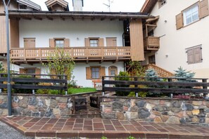 A multi-story building with wooden balconies and a stone wall in front.