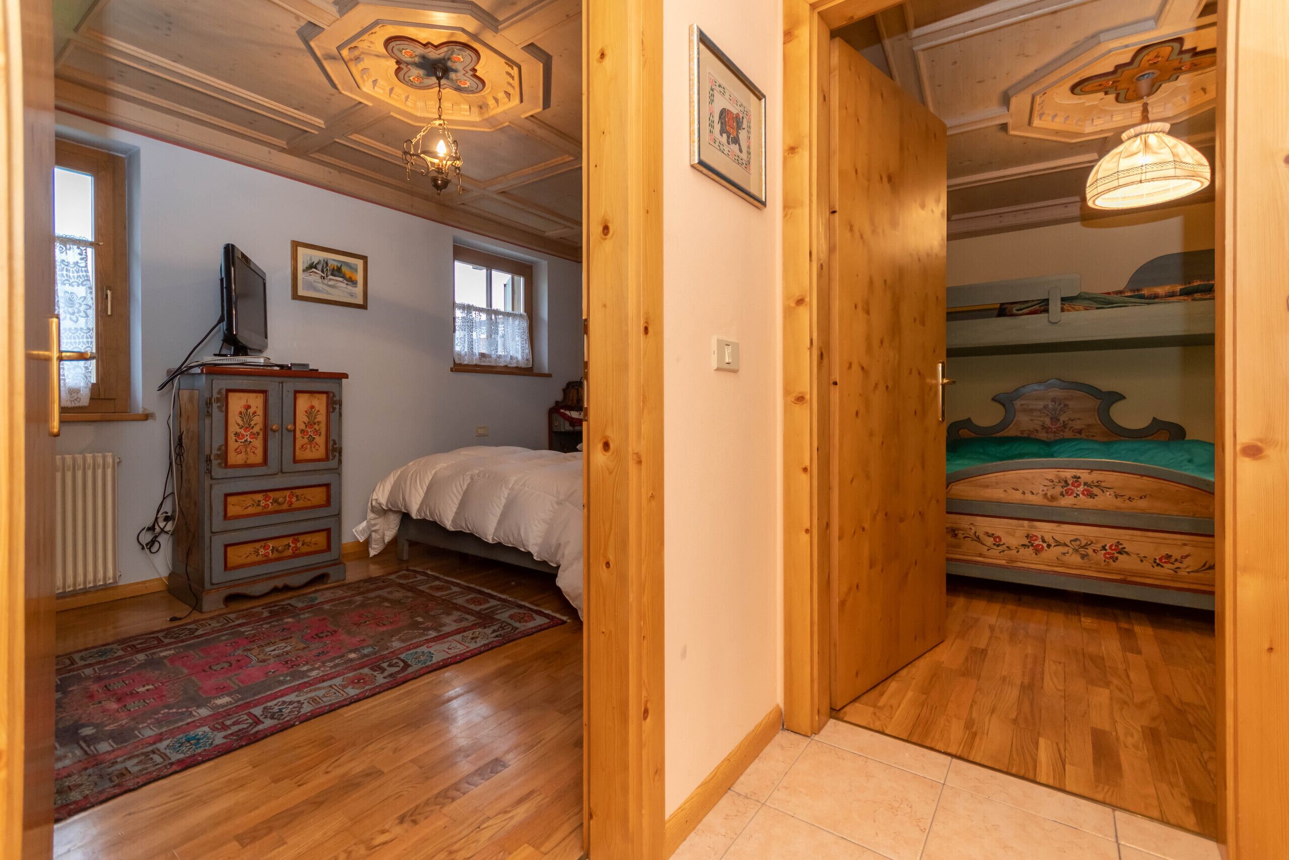 A bedroom with a wooden ceiling, a bed, a dresser, and a window.
