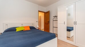 Une chambre à coucher comprenant un lit, une armoire et une porte donnant sur une autre pièce.