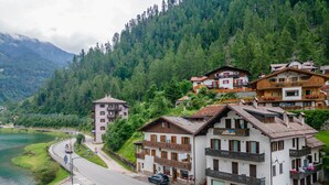 Un hôtel à étages, doté de balcons et offrant une vue sur un lac et des montagnes boisées.