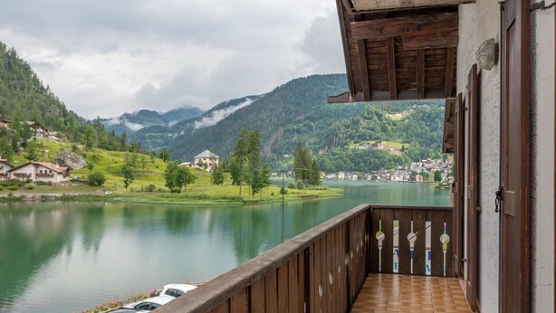 Un balcon offrant une vue sur un lac, des montagnes et une ville en arrière-plan.