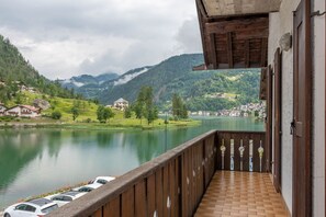 Un balcón con vistas a un lago, montañas y un pueblo al fondo.