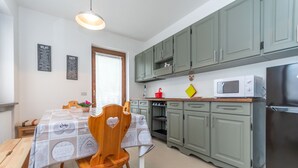Une cuisine avec des meubles de rangement verts, un four à micro-ondes et un réfrigérateur.