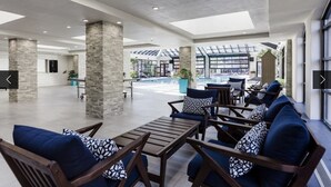 A spacious indoor area with a pool, seating arrangements, and a view of the outdoors.