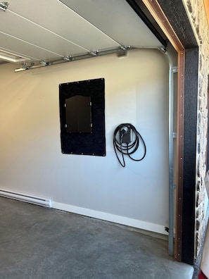 Un garaje con un panel de fieltro negro, un cable negro enrollado y una estructura de vigas de metal.