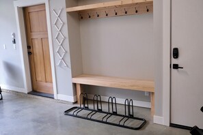 Un pasillo con puerta de madera, perchero, estante y soporte para bicicletas.