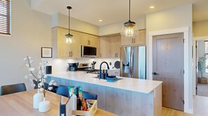 A modern kitchen with a central island, stainless steel appliances, and pendant lighting.