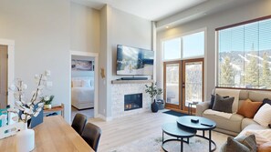 A modern living room with a fireplace, a television, a sofa, and a dining area.