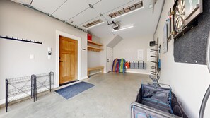 A room with a wooden door, a bench, a wall-mounted rack, and a ceiling projector.