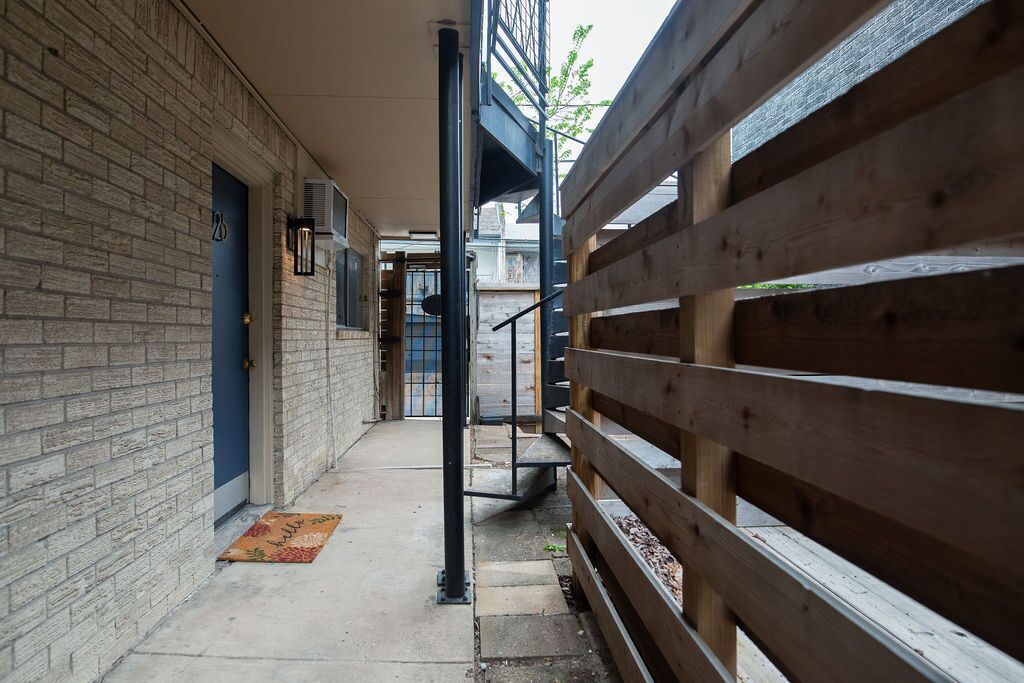 Un pasillo estrecho con una valla de madera, un muro de ladrillo y una puerta azul.