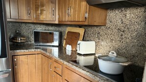 A kitchen with wooden cabinets, a microwave, a toaster, and a large pot on the counter.