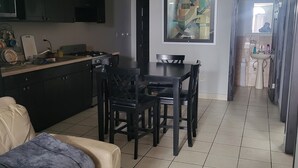 A modern kitchen with a dining area, a sofa, and a tiled floor. - Departamentos velasco (Tijuana)