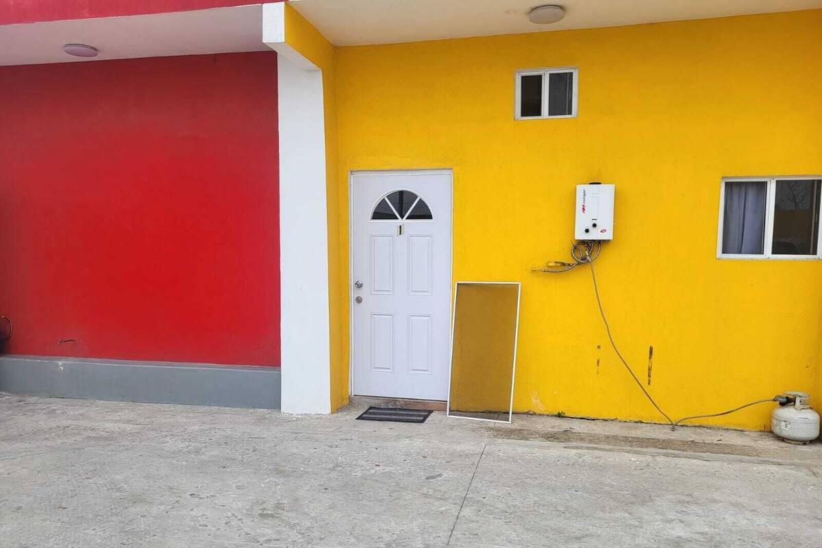 A building with a red and yellow facade, a white door, and a small window.