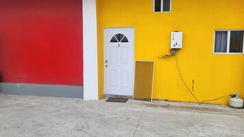 A building with a red and yellow exterior, a white door, and a small window.