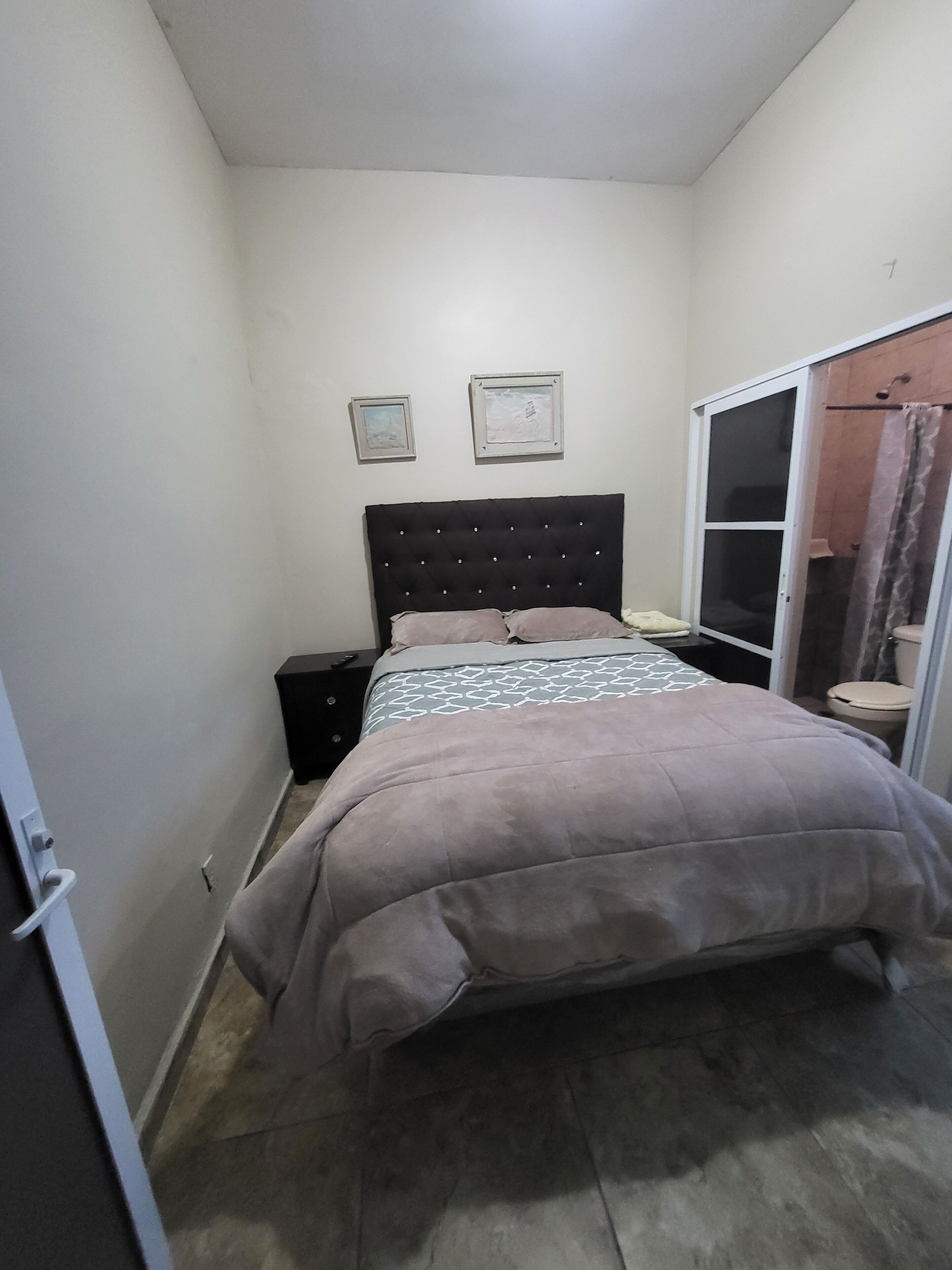 Une chambre à coucher avec un lit, une table de chevet, une armoire et deux tableaux encadrés au mur.