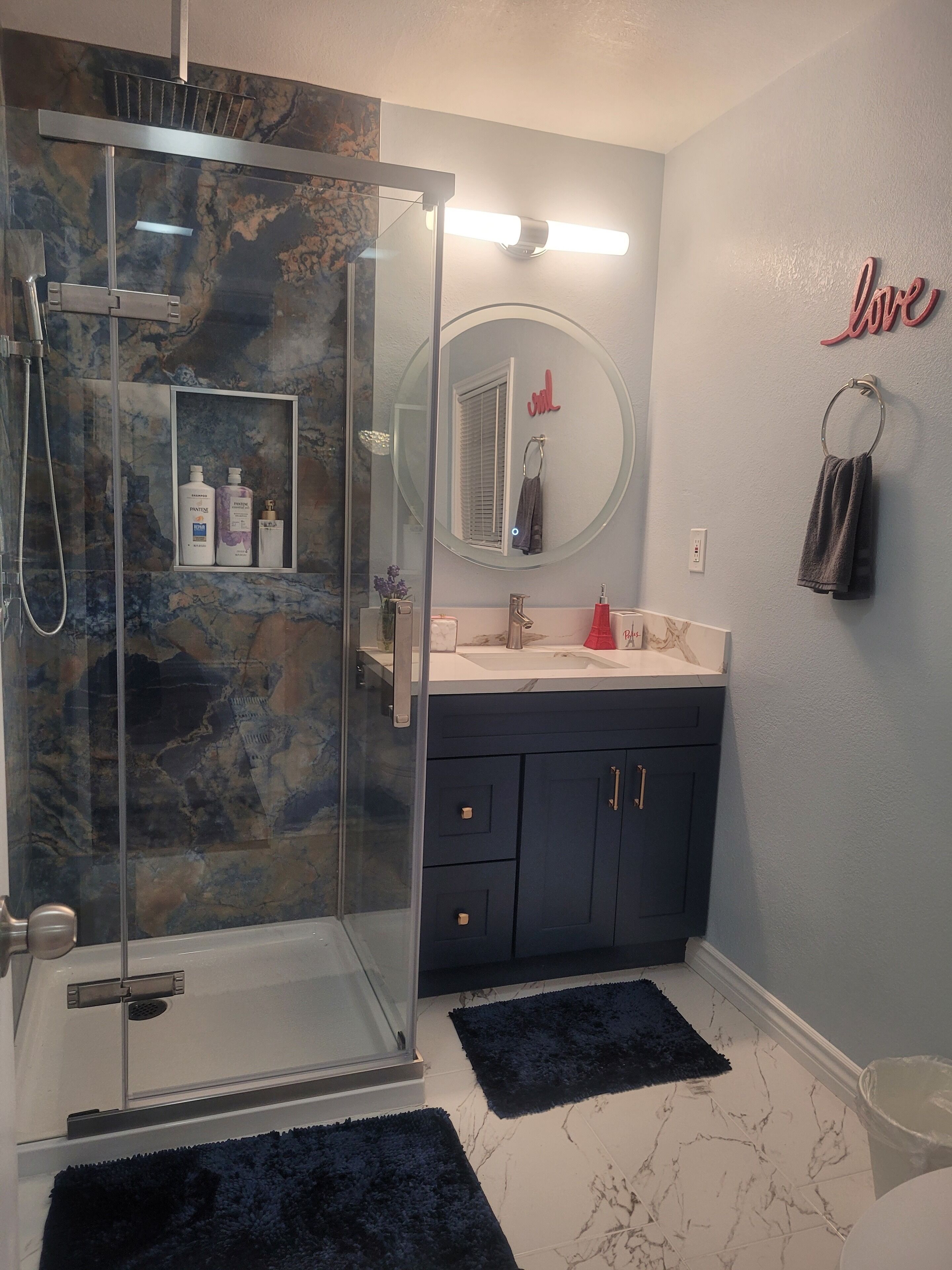 A bathroom with a glass-enclosed shower, a vanity with a mirror, and a towel rack.