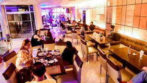 A modern restaurant with a long counter and booths, featuring a stage for live music in the background. - Rajah Park Hotel by Hiverooms (Cebu City)
