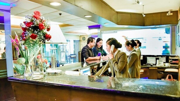 A reception area with a counter, a vase of flowers, and a clock on the wall. - Rajah Park Hotel by Hiverooms (Cebu City)