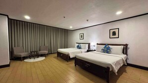 A hotel room with two single beds, a chair, a small table, a round rug, and a large window with curtains. - Rajah Park Hotel by Hiverooms (Cebu City)
