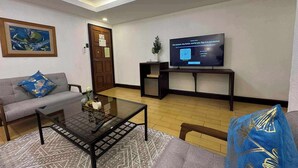A living room with a sofa, coffee table, and a television on a stand. - Rajah Park Hotel by Hiverooms (Cebu City)