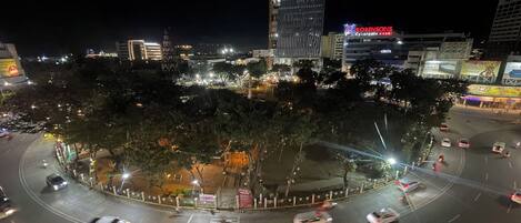 A roundabout with trees and illuminated buildings in the background.
