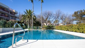 A swimming pool with a metal ladder, surrounded by palm trees and a hedge. - Les Coralines by Interhome (Villeneuve-Loubet)